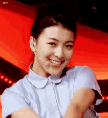 a close up of a woman wearing a microphone and smiling with the word reve in the corner