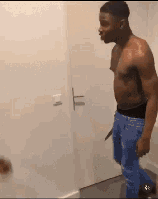 a shirtless man is standing in front of a door holding a knife in his hand .