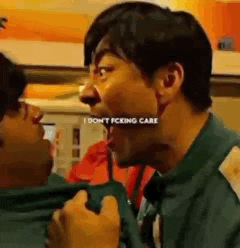 a man is making a funny face while talking to another man in a room .