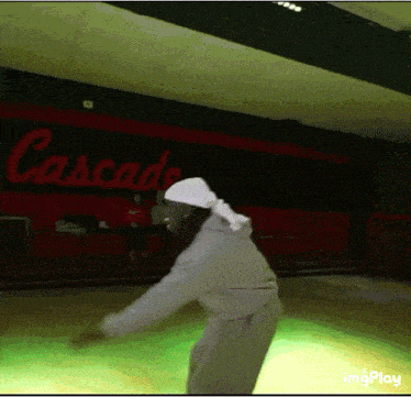 a person dancing in front of a cascade sign