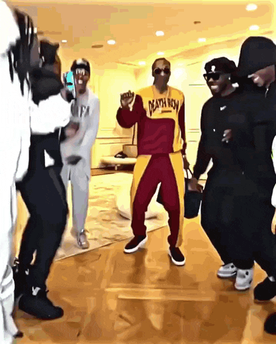 a group of men are dancing with one wearing a yellow death row shirt