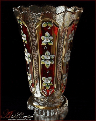 a red and gold vase with flowers painted on it is from a company called aek 's crystal