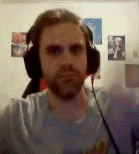 a man with a beard is wearing headphones and making a face .