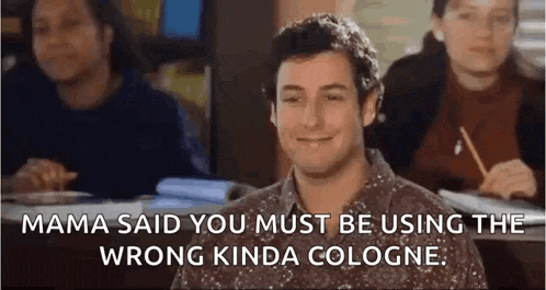 a man is sitting in a classroom with other people and smiling while using the wrong kind of cologne .
