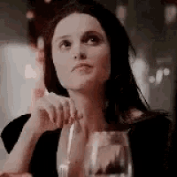 a woman is sitting at a table with a glass of wine .