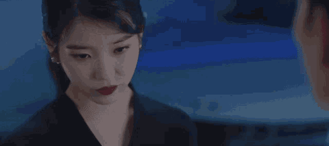 a woman with red lipstick is looking at a man in a dark room .