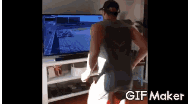 a man is standing in front of a television with a gif maker on the bottom