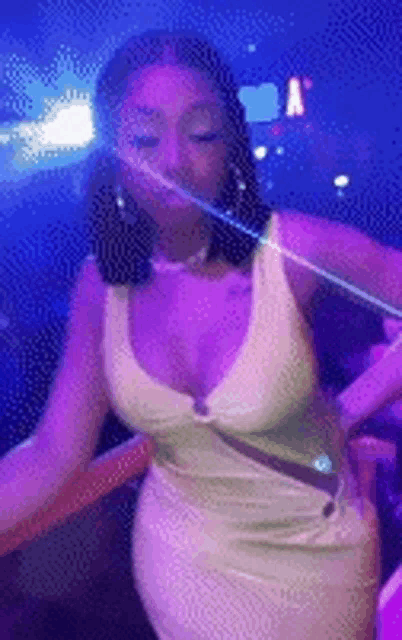 a woman in a white dress is dancing in a nightclub with purple lights .
