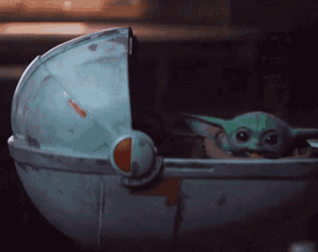 a baby yoda is sitting in a stroller with its mouth open