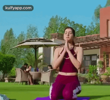 a woman is kneeling on a yoga mat in front of a house .