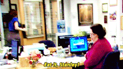 a woman is sitting at a desk with a computer and says eat it stanley