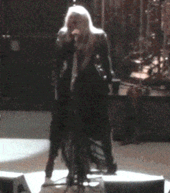 a woman sings into a microphone on a stage