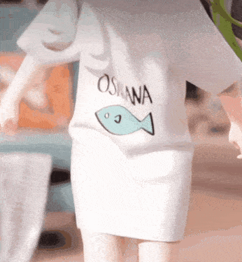 a person wearing a white shirt that says oshana with a fish on it