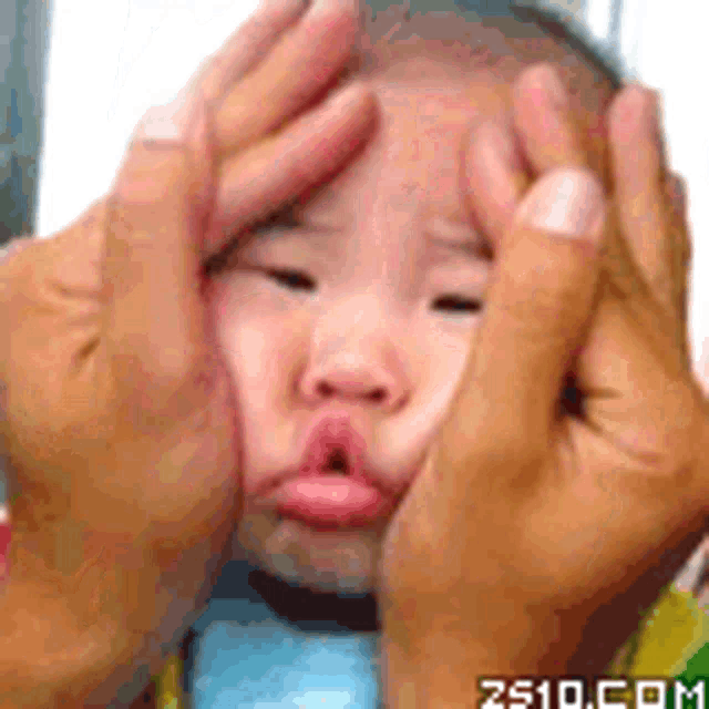 a baby is making a funny face with his hands on his face .