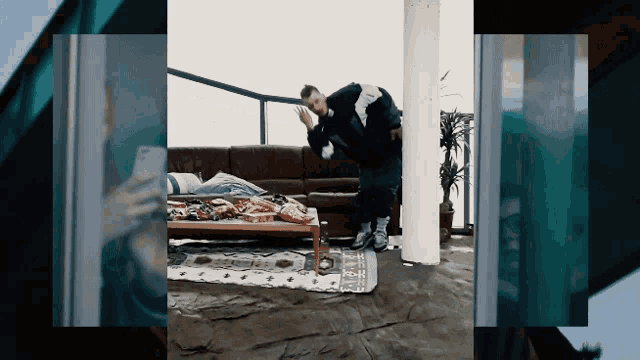 a man is standing in a living room with a couch and pizza on the floor