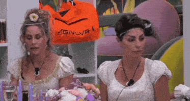 two women sitting at a table with an orange bag that says givova