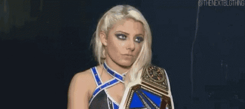 a woman is holding a wrestling championship belt in her hand .
