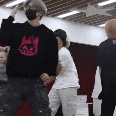 a man wearing a mask and a black sweatshirt with a crown on it