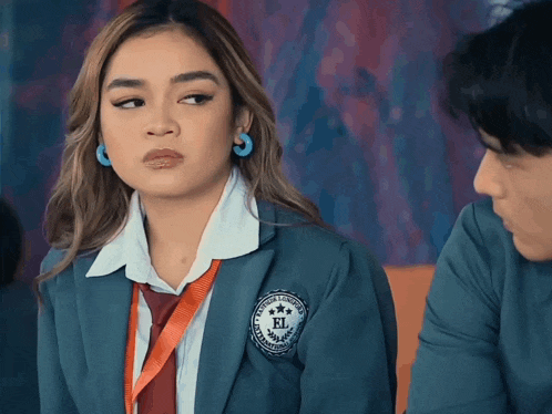 a girl in a school uniform has a badge that says el on it