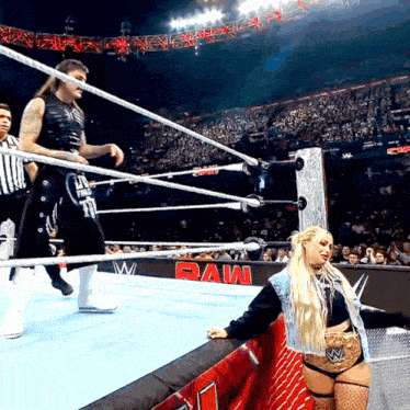 a woman stands in a wrestling ring with the word raw on the side