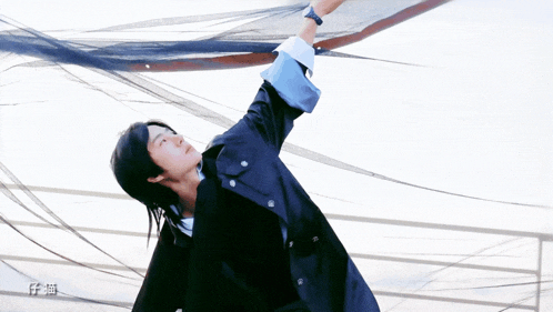 a man in a blue jacket is reaching up into the sky