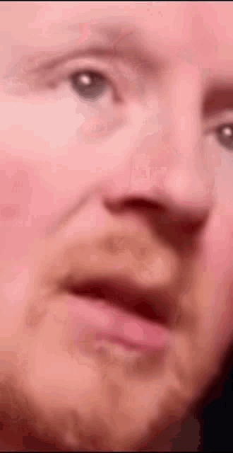 a close up of a man 's face with a beard making a face .