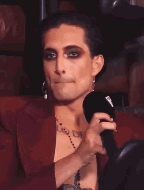 a man with makeup on his face and a tattoo on his chest is wearing a red jacket .