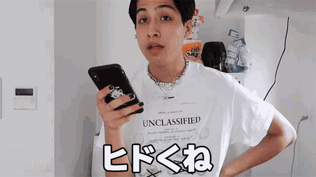 a man wearing a shirt that says unclassified is holding a phone