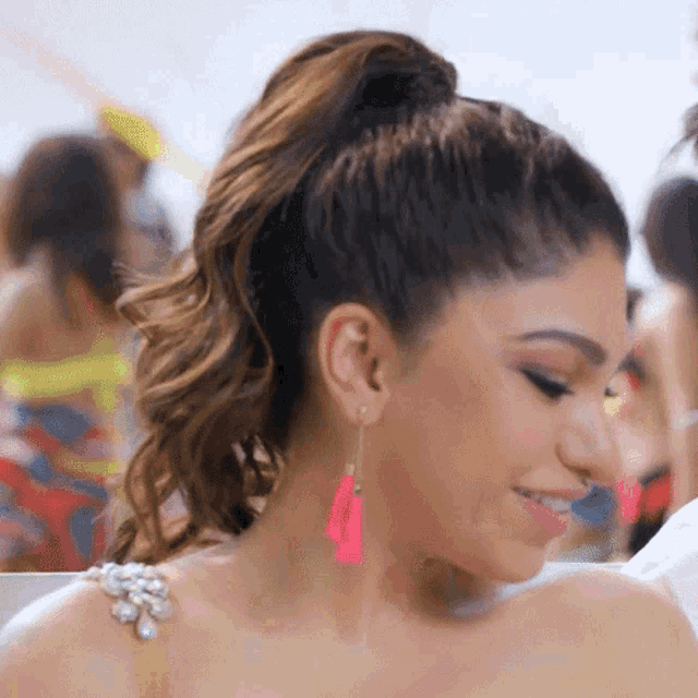 a woman wearing pink earrings and a ponytail