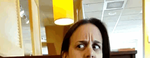 a woman making a funny face with a yellow lamp behind her