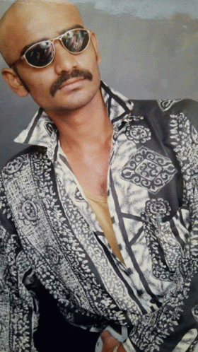 a bald man with a mustache wearing sunglasses and a shirt with a pattern