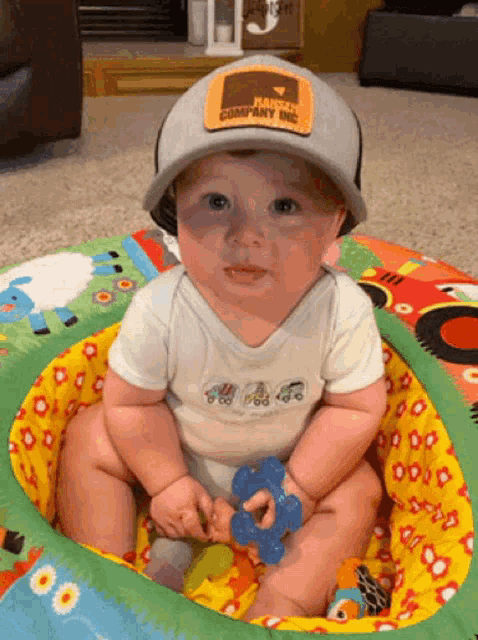 a baby wearing a hat with a patch that says farm company on it