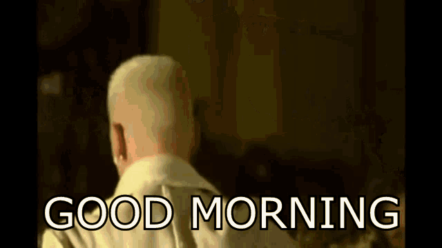 a man is sitting on a couch with the words `` good morning '' written on the bottom .
