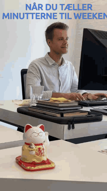 a man sits at a desk with a statue of a cat on it