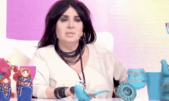 a woman sitting at a table with a blue teapot in her hand