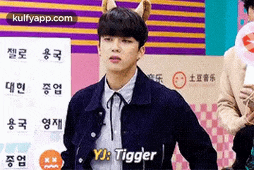 a young man wearing a dog ear headband is standing in front of a sign that says tigger .