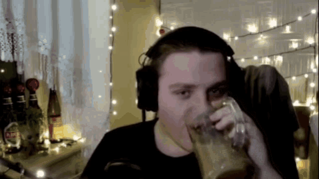 a man wearing headphones is drinking a beer from a mug .