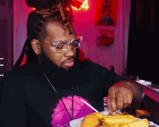 a man with glasses is eating a hamburger and french fries