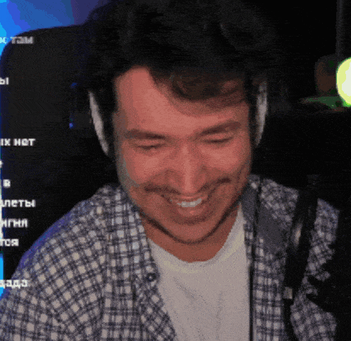 a man wearing headphones and a plaid shirt is smiling in front of a computer screen that says ix hot