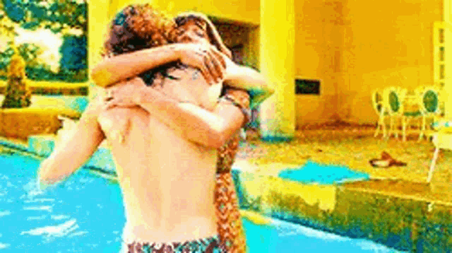 a man and a woman are hugging each other in a pool .