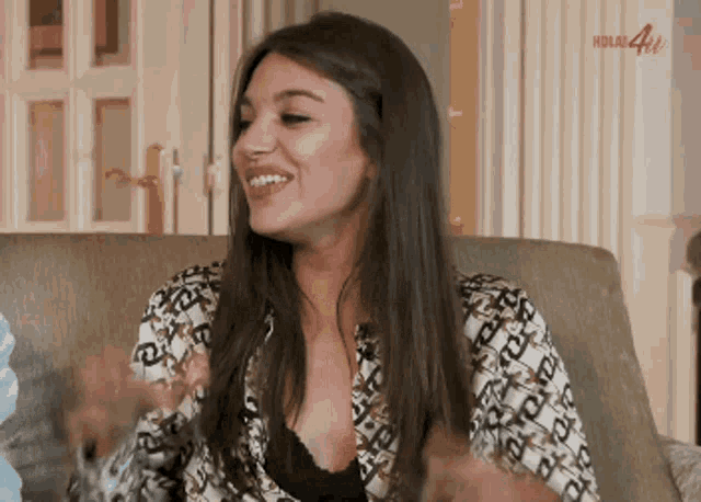 a woman is sitting on a couch with her arms outstretched and smiling .