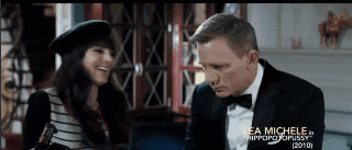 a man in a tuxedo and bow tie is talking to a woman in a hat ..
