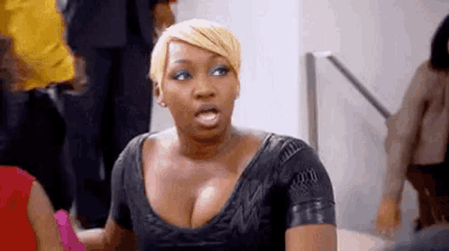 a woman in a black dress is making a funny face while standing in front of a crowd of people .