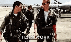 two men in military uniforms are standing next to each other on a runway and talking .