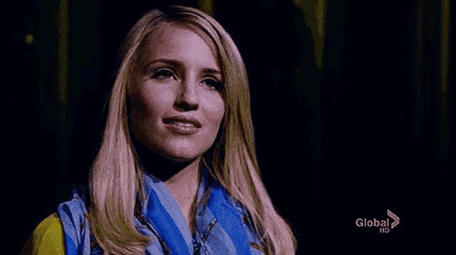 a close up of a woman wearing a blue scarf and a yellow jacket .
