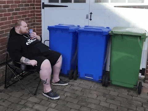a man wearing an ellesse sweatshirt sits in a chair drinking a beer