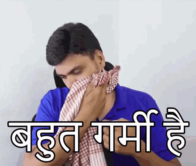 a man in a blue shirt wipes his nose with a checkered towel with a caption in a foreign language