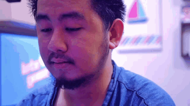 a man with a beard wearing a blue shirt looks at something