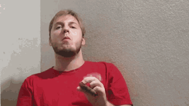 a man in a red shirt smoking a cigarette