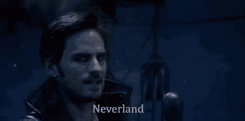 a man in a black jacket is standing in a dark room with the word neverland written on the bottom .